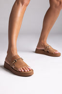 Brown sandals worn by a person on a light gray background