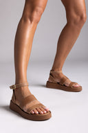 Brown sandals worn by a person on a light gray background