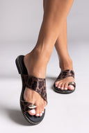 Leopard print sandals worn by a person on a light gray background