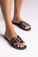 Leopard print sandals worn by a person on a white background
