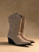 Pair of beige cowboy boots on a beige background